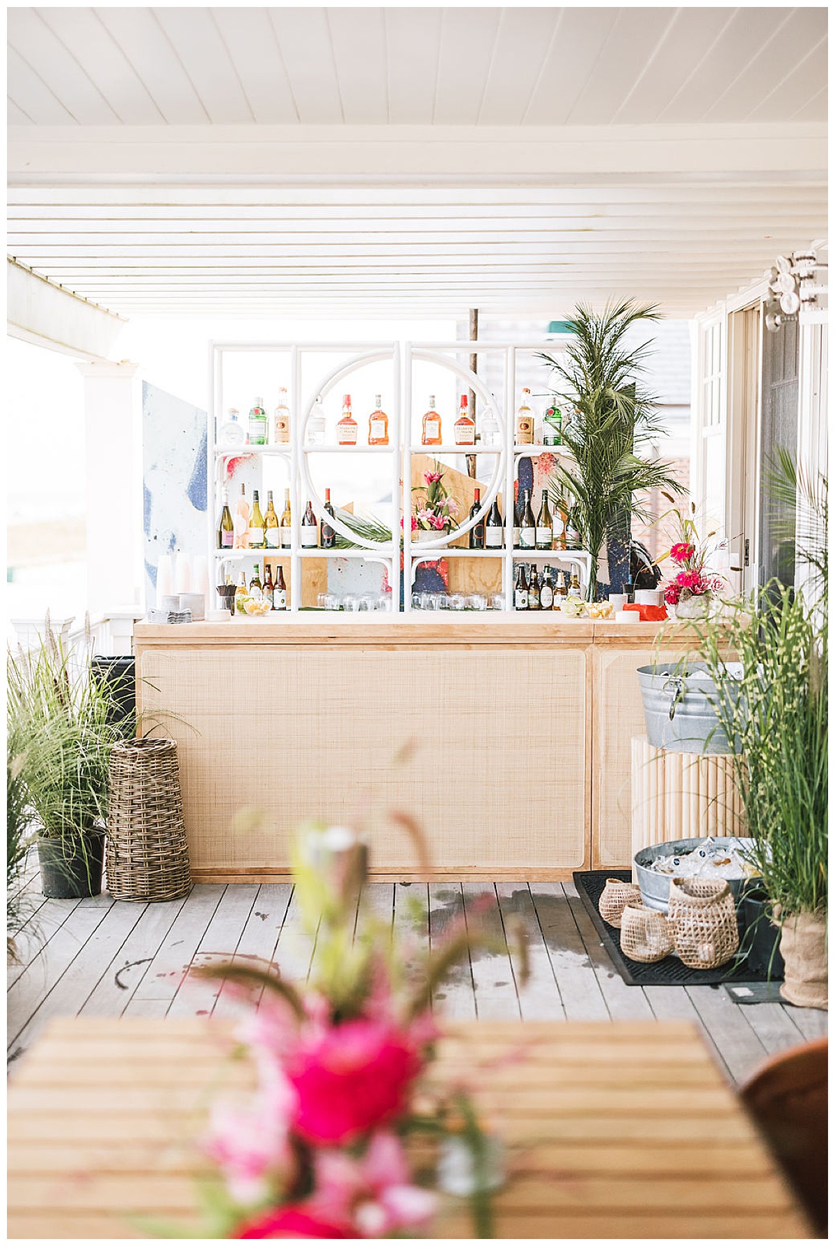 A beach-y caned bar with midcentury white bamboo bar back.