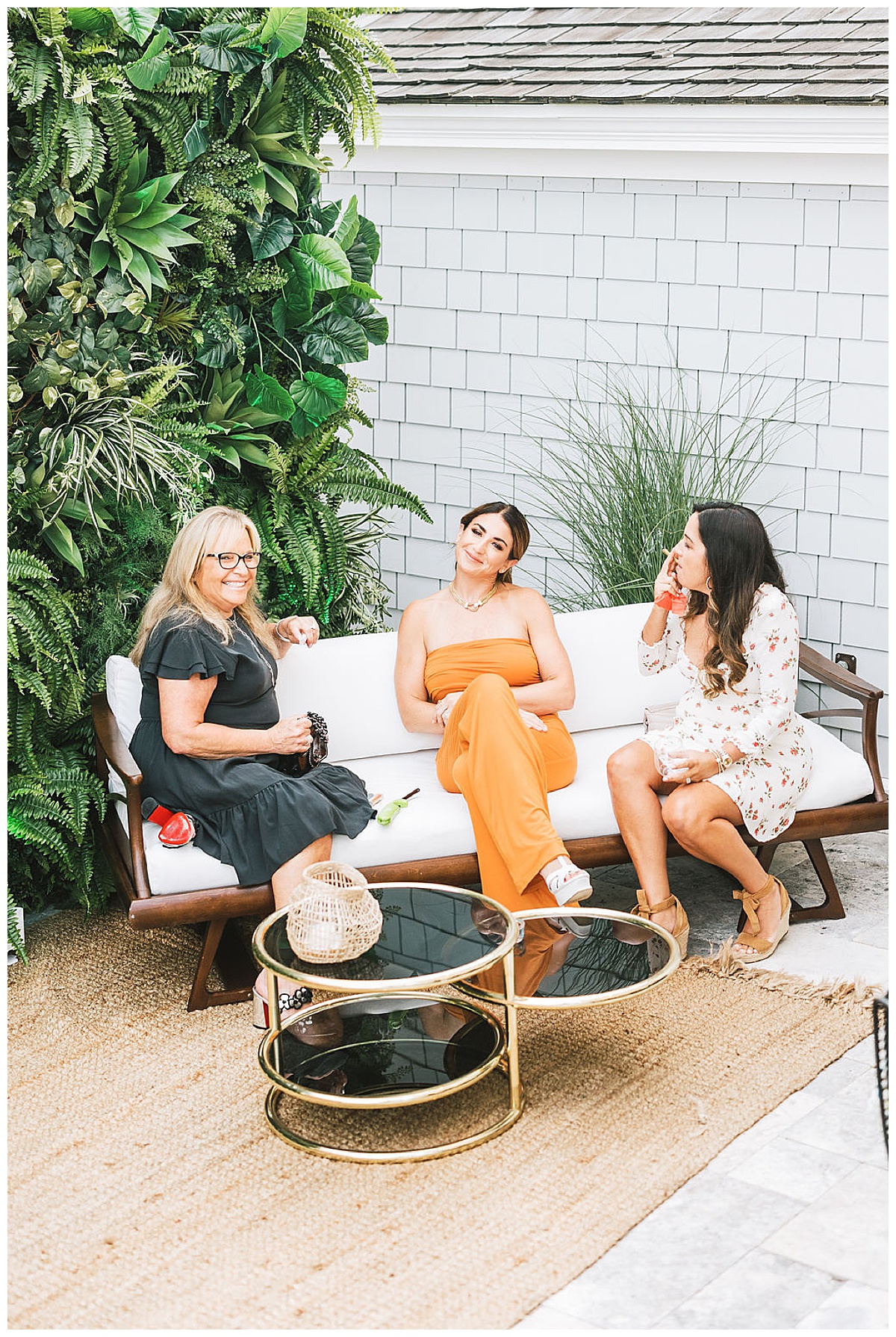 Three girls lounging on a white midcentury sofa.