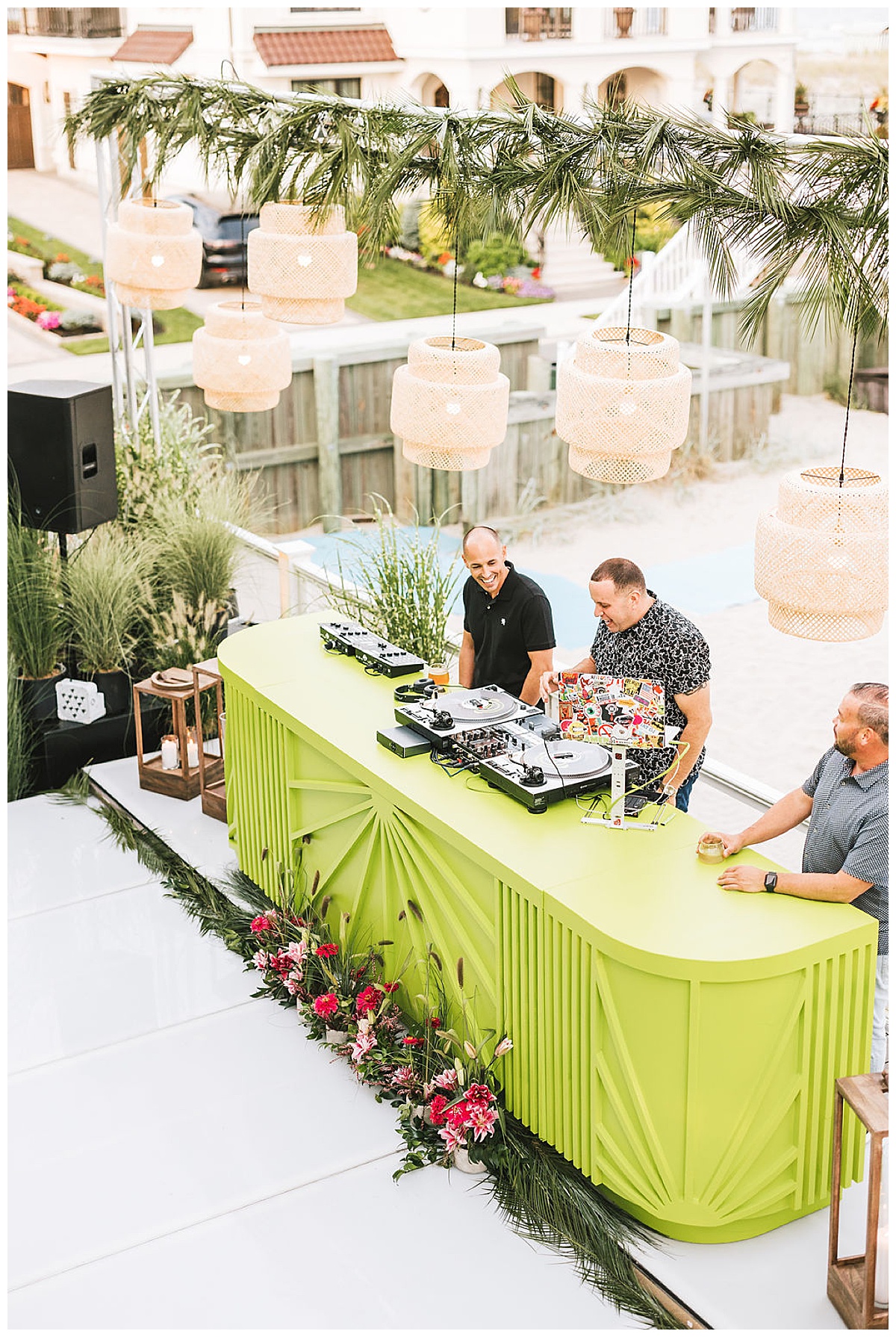 A lime green DJ booth set up on the beach with bamboo pendant lights hanging overhead.
