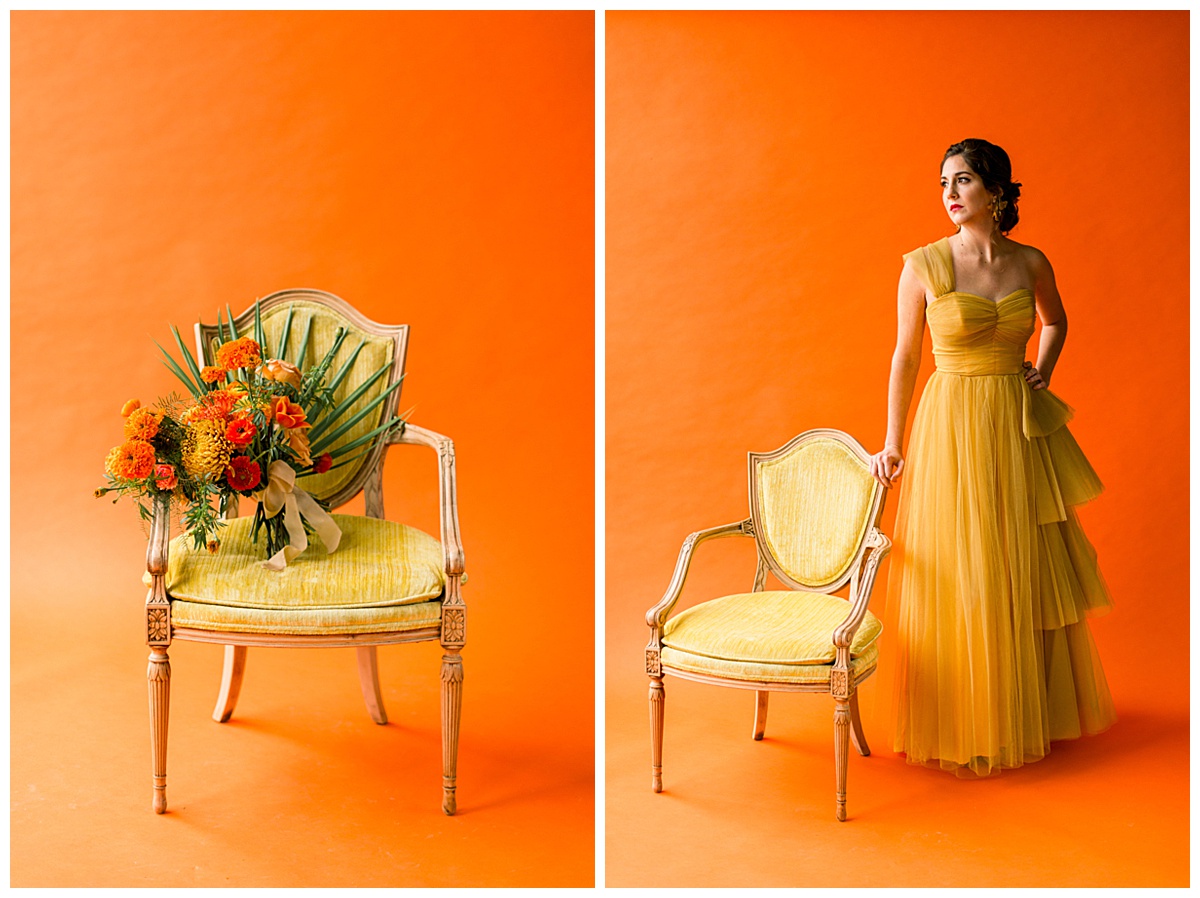 A vintage yellow velvet chair is displayed in front of an orange backdrop and topped with a tropical wedding bouquet.