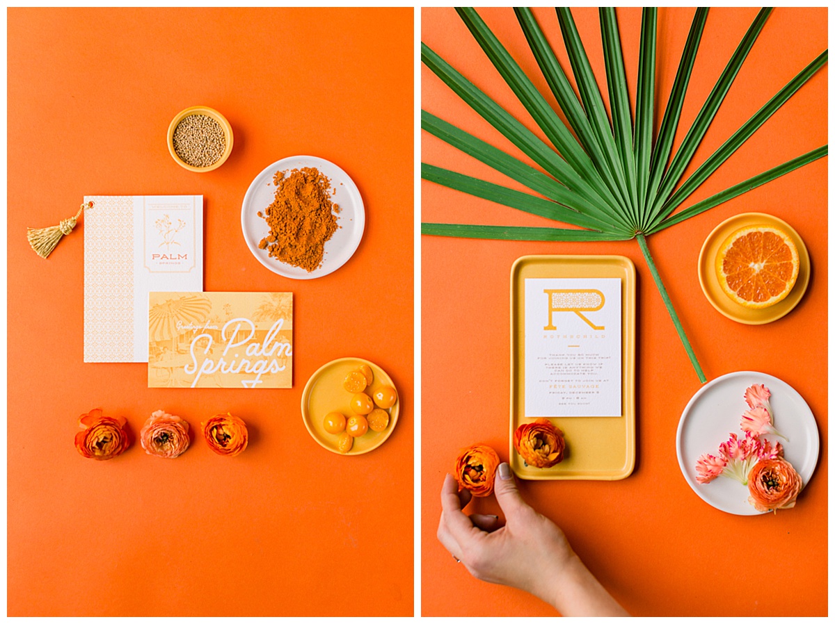 A marigold paper suite is styled on an orange backdrop with orange carnations and tropical palm frond.