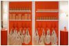 Custom pegboard display in bright orange with shelves of event favors, showcasing a thoughtful party favor setup for the Verona Sunset-themed event by Something Vintage Rentals.