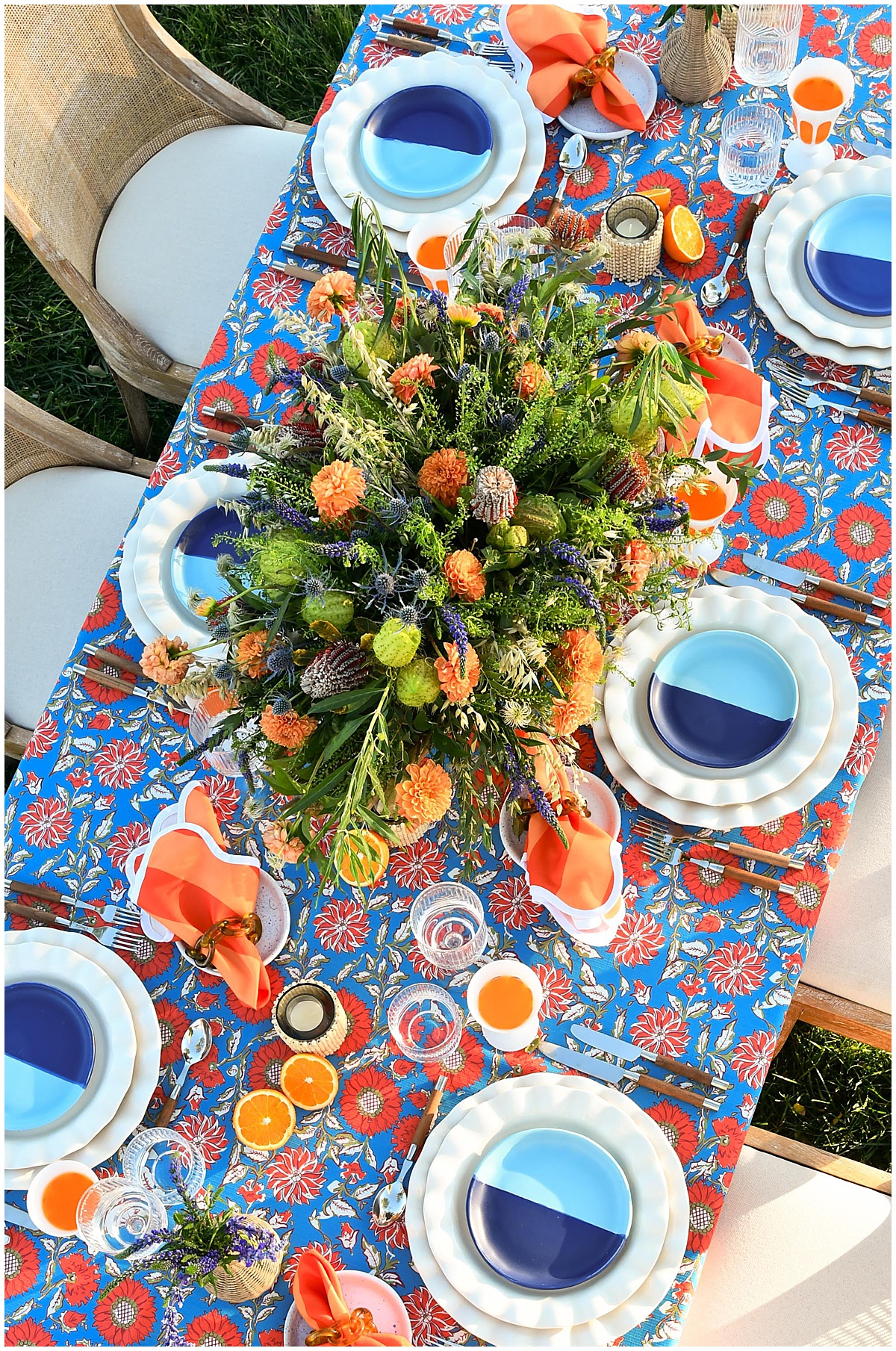 Blue and orange patterned linen table setup with bright florals, citrus details, and modern dinnerware, styled as part of the OG linen collection from Something Vintage Rentals, the U.S. East Coast’s best event rental and wedding decor company.