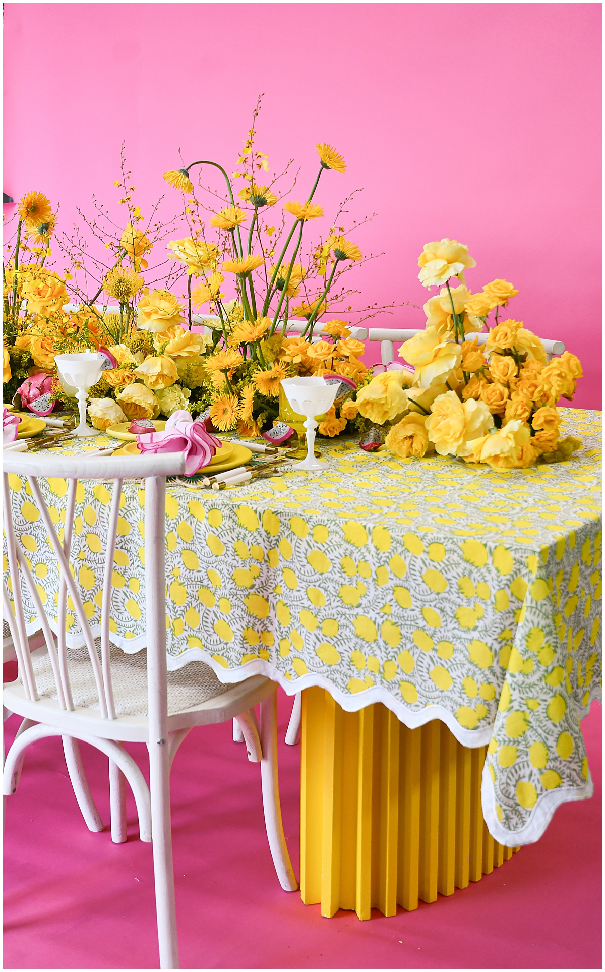 Yellow and white patterned linen with scalloped edge, styled with monochrome yellow florals and pink ribbons for a playful tablescape from the OG linen collection by Something Vintage Rentals, the U.S. East Coast’s best event rental and wedding decor company.